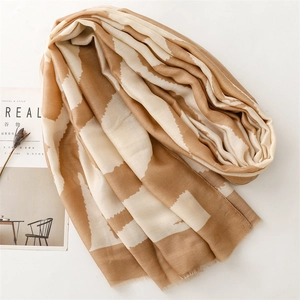 Detail of soft khaki geometric wave pattern scarf with delicate fringe edges on white