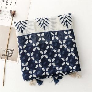 Detail of blue and white scarf with leaf patterns, floral prints and tassel fringe