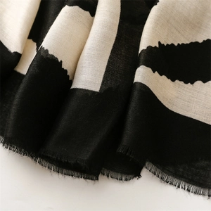 Close-up of geometric striped scarf showing fine fabric texture and frayed fringe edges