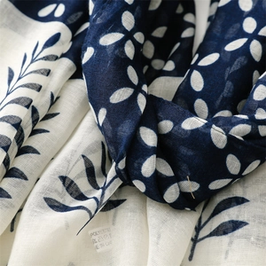 Close-up of blue floral scarf texture and washing label showing polyester material