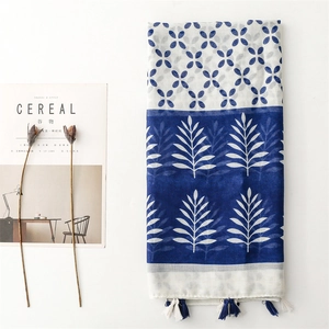 Detail of blue and white geometric floral scarf with tassels and aesthetic magazine
