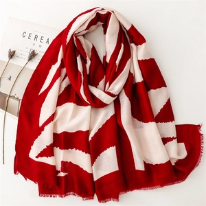 Geometric red and white striped lightweight scarf displayed with lifestyle props