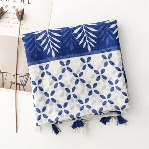 Detailed close-up of blue and white floral scarf with delicate fringe tassels and tassels