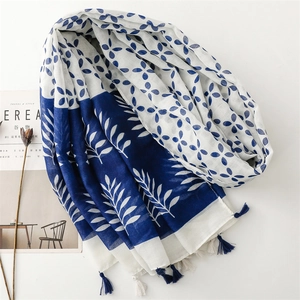 Detailed view of lightweight blue and white floral scarf with decorative tassels