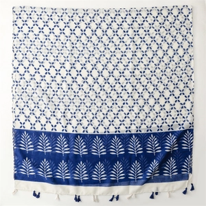 Detailed view of blue and white floral scarf with leaf patterns and tassels