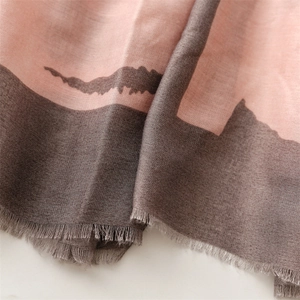Close-up of soft pink and taupe knit scarf featuring tassel edges and abstract prints