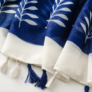Close-up of ethnic blue and white scarf featuring leaf prints and handmade tassels