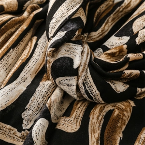 Detail of soft woven scarf fabric with abstract geometric patterns in black and caramel