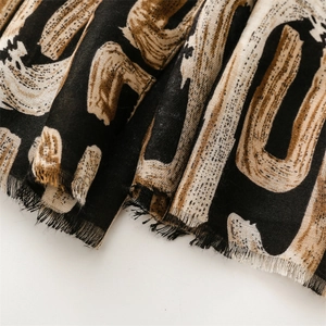 Macro detail of geometric alphabet print scarf with soft texture and fringed edges