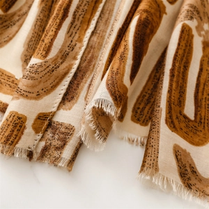 Close-up of geometric letter print scarf with fringe edges on marble surface