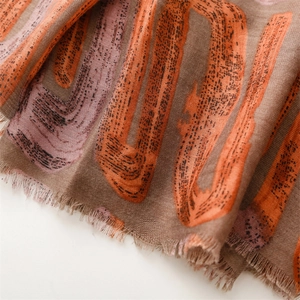 Close-up of geometric print scarf with linen feel texture and delicate tassel edges