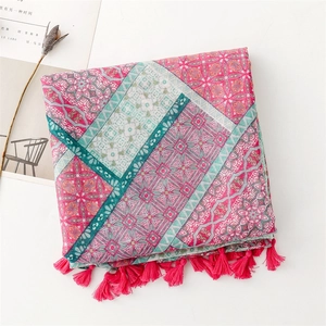 Dettaglio sciarpa bohémien con motivi geometrici rosa e verdi e frange con nappine
