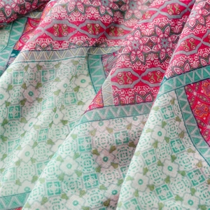 Dettaglio di motivi boho rosa e verdi su una sciarpa in tessuto leggero e sottile