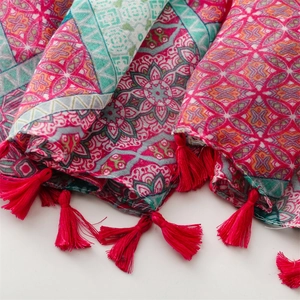 Dettaglio di sciarpa bohémien con motivi mandala, nappe rosa e disegni geometrici vivaci