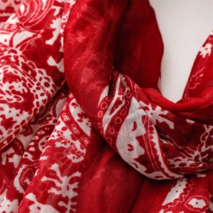 Détail de l'imprimé cachemire rouge et texture de pompons sur châle bohème léger