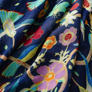 Detailed view of floral bird print on dark blue lightweight scarf fabric with soft drape
