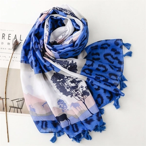 Blue leopard print scarf with deer landscape design and elegant tassel trim on white table