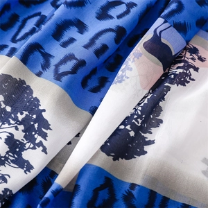 Detail of thin scarf fabric with blue leopard print and tree silhouette pattern