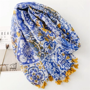 Écharpe florale bohème bleu et jaune avec pompons sur fond blanc minimaliste