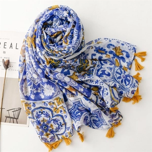 Détail d'une écharpe à motifs de fleurs bleues avec de jolis pompons jaunes