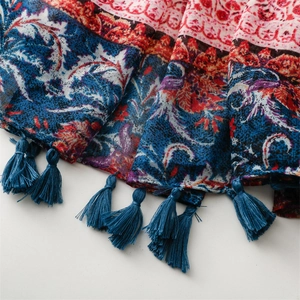 Macro detail of bohemian cotton-linen scarf with ethnic prints and blue tassel fringe