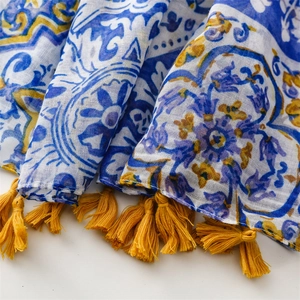 Gros plan d'une écharpe bleue et blanche avec des glands jaunes et des motifs floraux