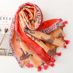 Close-up of lightweight leopard print scarf with orange-pink contrast and fringe details