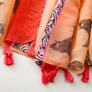 Detail of vibrant orange leopard print scarf showing soft fabric texture and red fringe