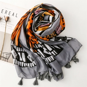 Detail of bohemian scarf with leopard print, geometric waves and grey tassel fringes