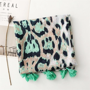 Detailed close-up of green leopard print scarf with delicate mint fringe tassels