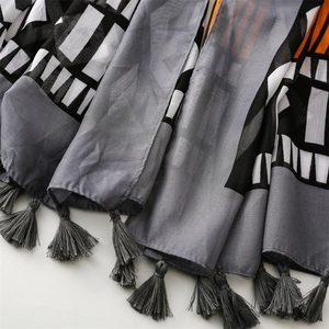 Detail of geometric print scarf showing sheer fabric texture and grey fringe tassels