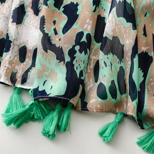 Detailed macro view showing the green leopard print fabric texture and tassel fringe edge