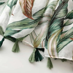 Detail view of tropical leaf print on breathable fabric with green tassels