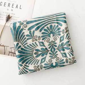 Detail of teal cotton-linen scarf with gold floral patterns next to a lifestyle magazine
