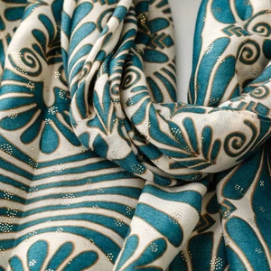 Detailed texture of lake blue linen scarf with gold floral foil print and raw edges