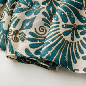 Close-up of teal leaf print scarf with sparkling gold glitter detail and fringe