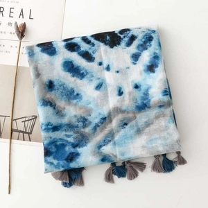 Detail of blue tie-dye scarf with fine tassel edges on a minimalist white surface