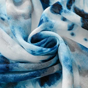 Detailed macro view of the blue tie-dye pattern and soft texture on woven scarf fabric
