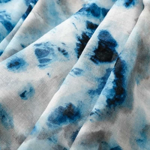 Detailed macro view of the breathable blue tie-dye fabric texture and fine fringe edge