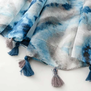 Detailed macro view of the breathable tie-dye scarf fabric with elegant tassel fringe