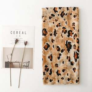 Close-up of leopard print cotton-linen scarf with raw fringe edges and gold foil accents