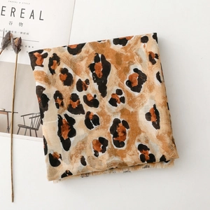 Flat lay of leopard print scarf with fringe edges beside Cereal magazine and dried flowers
