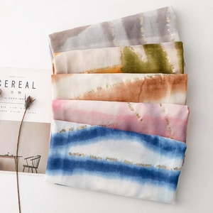 Détail de foulards en coton et lin empilés avec rayures dorées et motifs de teinture tie-dye