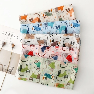 Detail showing various colors of cat and snowflake print scarves with soft fabric texture