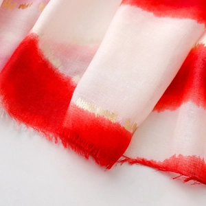 Détail macro d'une écharpe rayée rouge et blanc avec des touches de dorure à la feuille