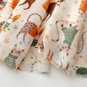 Macro detail of cat and snowflake print on soft cream textile scarf material