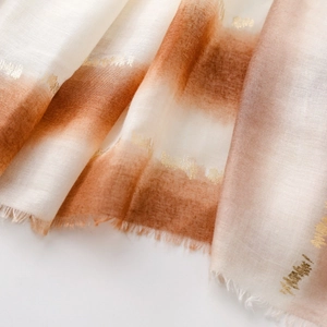 Détail de l'écharpe en coton et lin dégradé avec accents dorés élégants et des franges