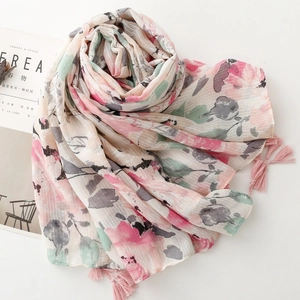 Detailed view of floral watercolor print scarf with pink tassel and linen-like texture