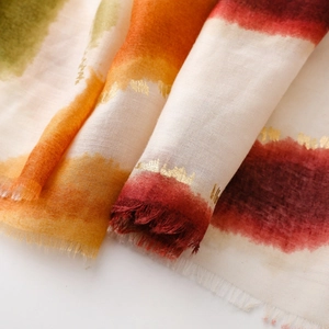 Détail de l'écharpe en coton et lin avec rayures aquarelle et accents de feuille d'or