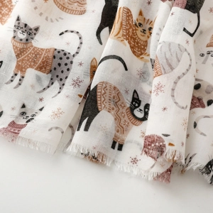Close-up of soft cotton-linen scarf featuring cute cartoon cats and pink snowflake prints